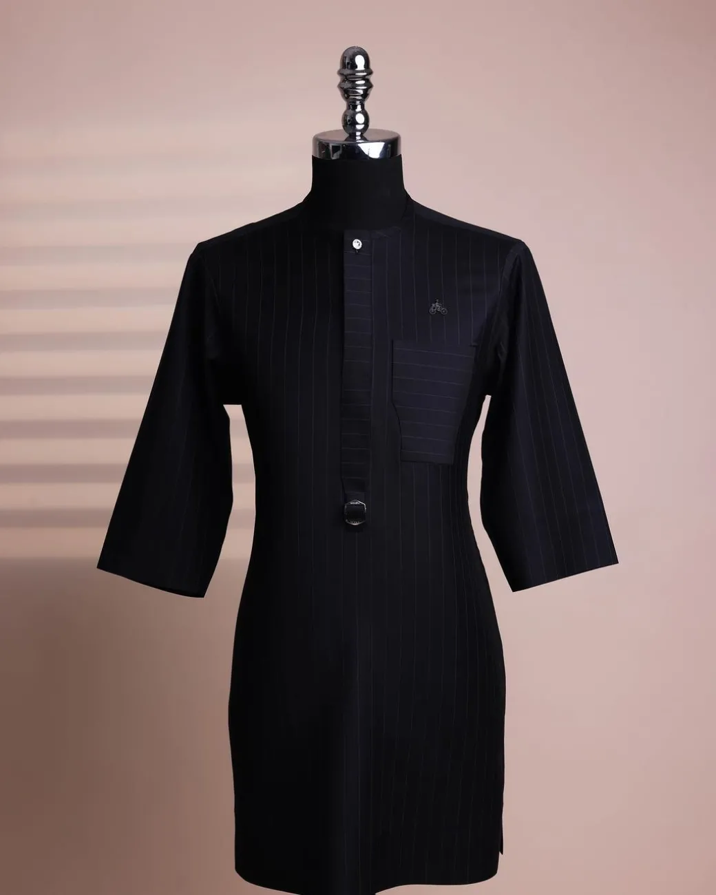 A black pencil stripe, mug-shaped pocket, front flap with buckle strap and silver Swarovski button, 3/4 sleeve African senator kaftan.