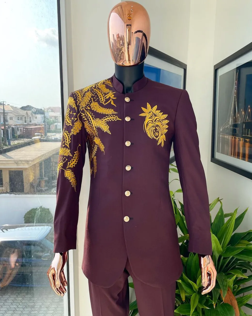 A burgundy safari suit with gold floral pattern embroidery detailing