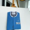 A cerulean blue, vertical flap with horizontal paisley patch pocket detailing and a Swarovski button African traditional senator kaftan native
