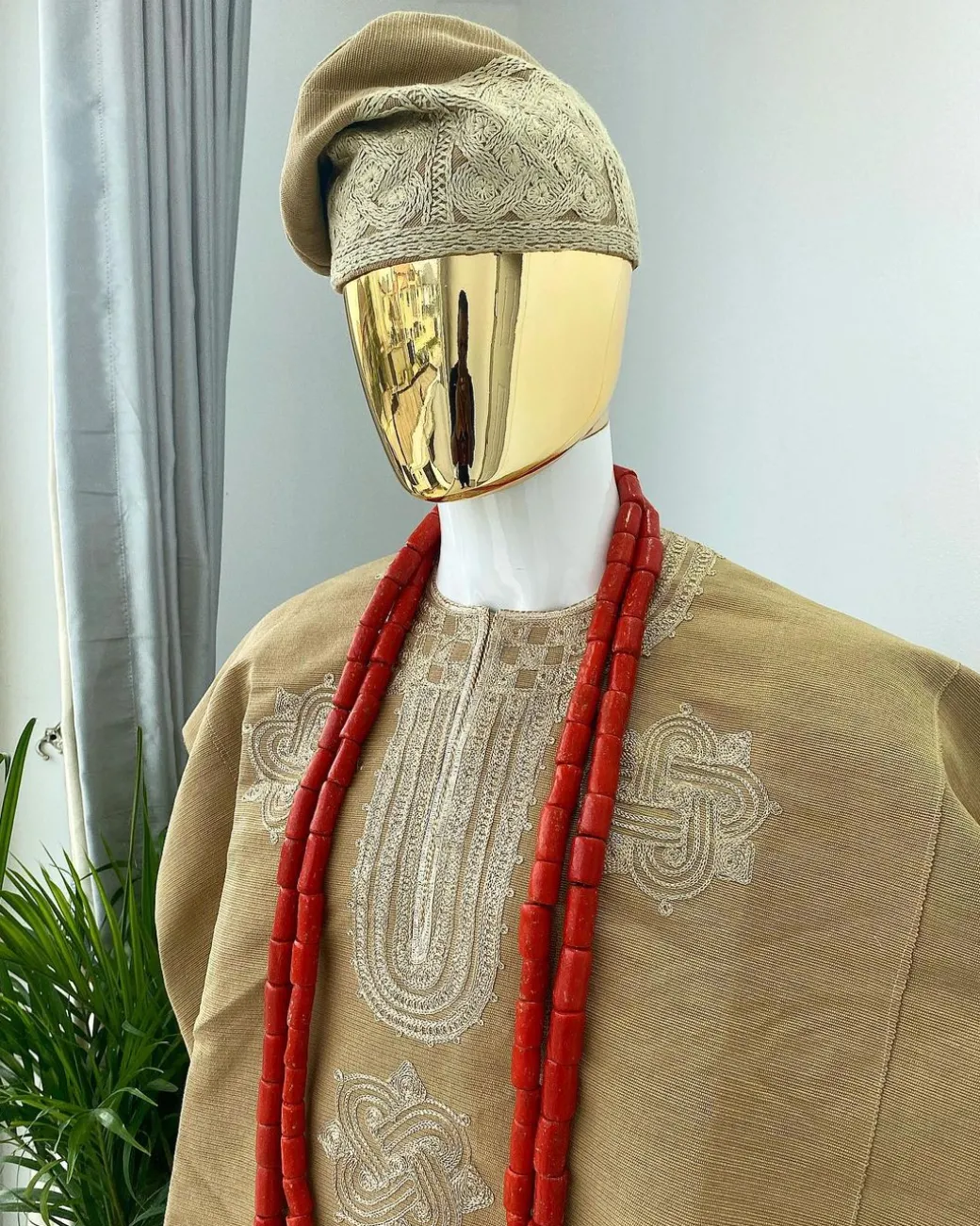 A champagne gold aso oke dashiki, with a floral and ancient style shaped embroidery design, hand woven Yoruba hat, an extra length red and gold coral bead.