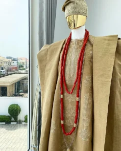 A champagne gold aso oke regal agbada, dashiki, sokoto, red and gold mix coral bead, matching hand woven Yoruba hat, and a long gold chain with a Jesus piece.