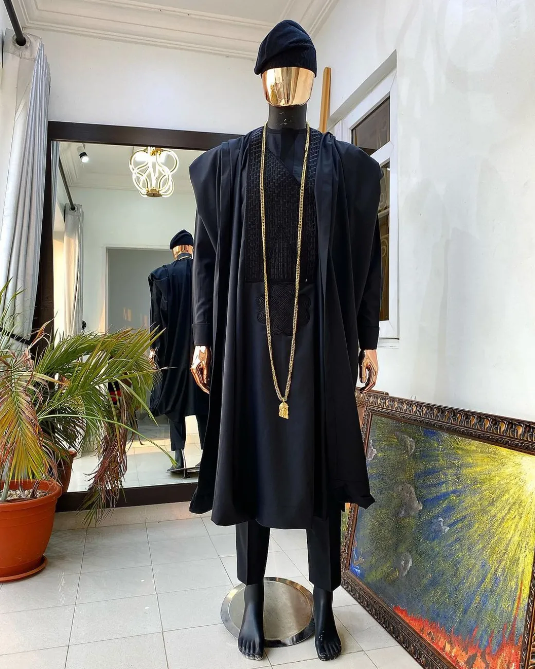 A charcoal black agbada, Jesus piece long fashion chain and hand woven aso oke Yoruba hat.