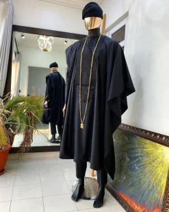 A charcoal black agbada, Jesus piece long fashion chain and hand woven aso oke Yoruba hat.