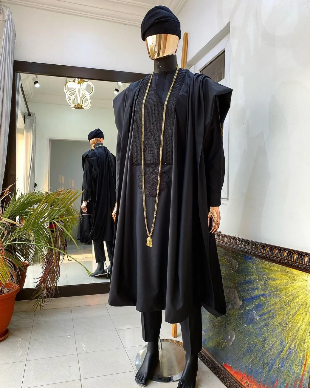 A charcoal black agbada, Jesus piece long fashion chain and hand woven aso oke Yoruba hat.