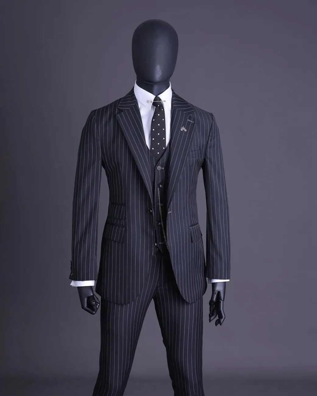A charcoal black and ivory pencil stripe, notch lapel, knitted one button suit