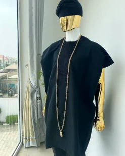 A charcoal black aso dashiki with a floral and box-shaped embroidery design, a hand-weaved Yoruba hat, and a gold Jesus timepiece