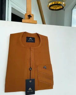 A ginger orange, mid section embrodery front flap with a symmetric lane patch pocket African traditional kaftan native.