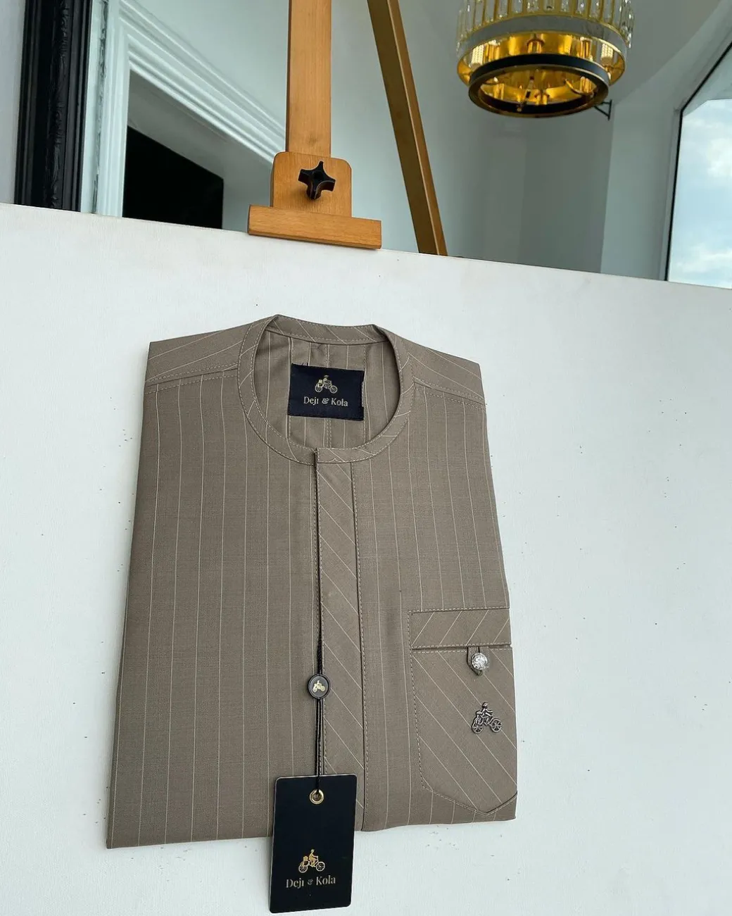 A pencil-striped tortilla brown front flap with an inverse combat pocket Swarovski button details African traditional senator Kaftan native