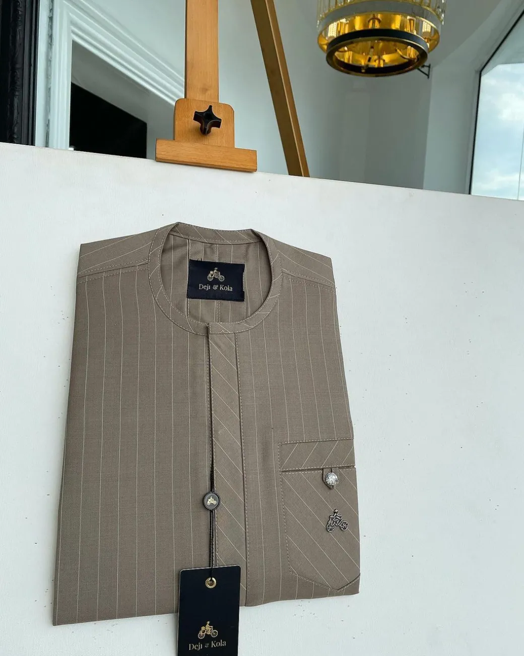 A pencil-striped tortilla brown front flap with an inverse combat pocket Swarovski button details African traditional senator Kaftan native