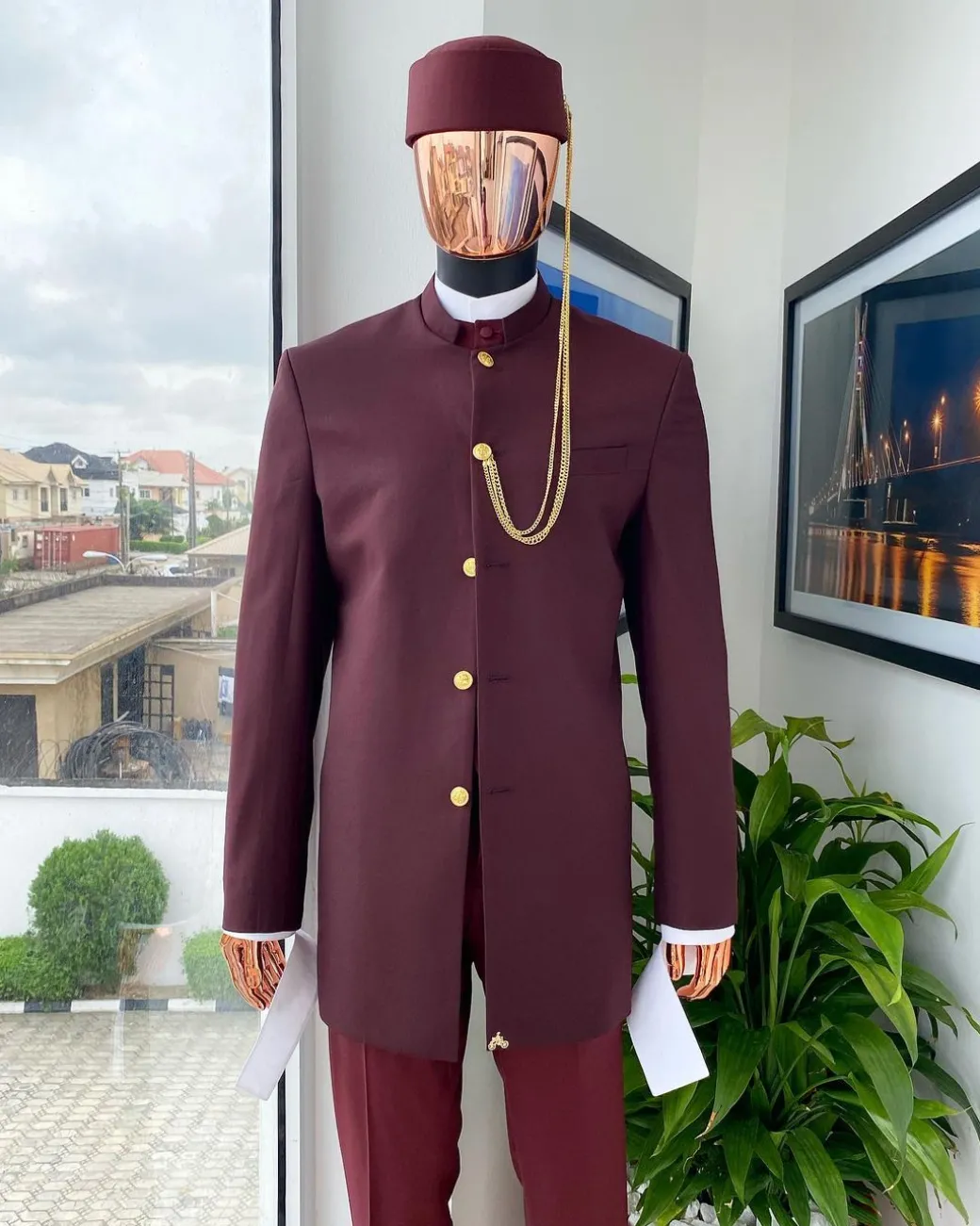 A Reloaded Ceremonial “Ayeye” Ijade 20/21 – Look 10- “Ajala”. A burgundy safari jacket with gold buttons, inner waist coat, turtle neck shirt, hat and pant trousers.
