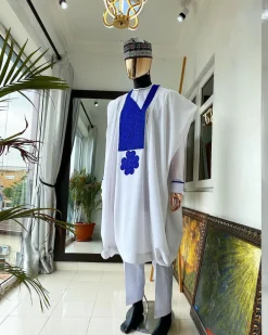 A white Agbada with royal blue embroidery detailing and royal blue Swarovski stone with hand woven Aboki hat