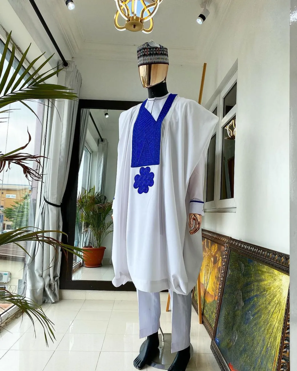 A white Agbada with royal blue embroidery detailing and royal blue Swarovski stone with hand woven Aboki hat