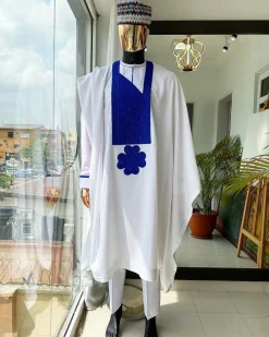 A white Agbada with royal blue embroidery detailing and royal blue Swarovski stone with hand woven Aboki hat